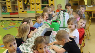 dzieci czekają na zajęcia przy stolikach