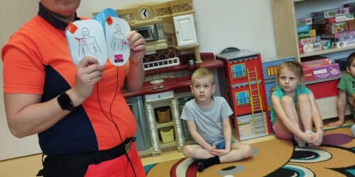 pani ratownik pokazuje dzieciom jak użyć defibryatora