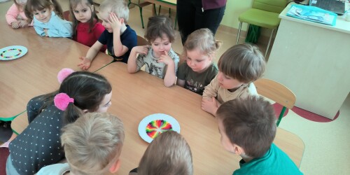 dzieci obserwują doświadczenie kolorową tęczę z cukierków
