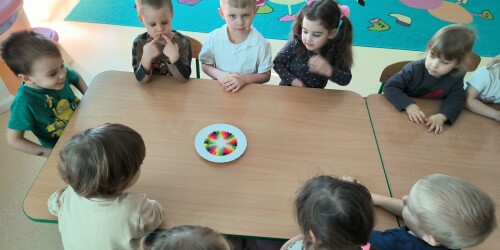 dzieci obserwują doświadczenie kolorową tęczę z cukierków