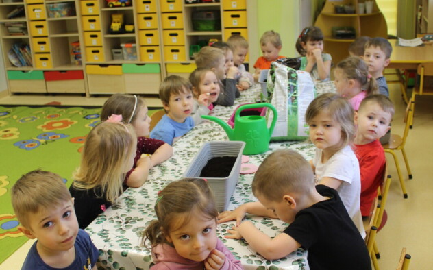 dzieci czekają na zajęcia przy stolikach