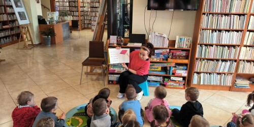 dzieci słuchają pani bibliotekarki jak czyta książkę